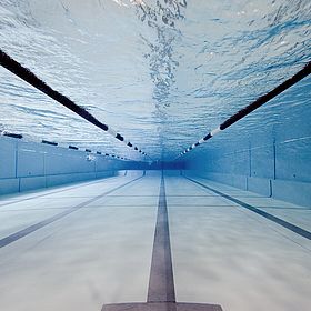 Das Bild zeigt eine Unterwasseransicht eines Schwimmbeckens. Die Perspektive ist so gewählt, dass man durch das Wasser in Richtung des Beckenendes blickt.