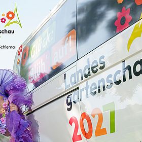 Sportpark Rabenberg EURORANDO 2026 Aussteller: Landesgartenschau 2027; © Dirk Rückschloß | pixore photography Landesgartenschau 2027 Aue-Bad Schlema mit einer Frau in Blumenkostüm vor einem Schriftzug auf einem Bus.