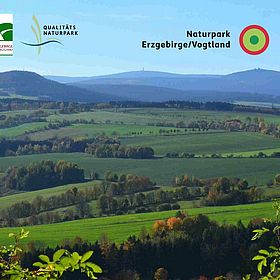Sportpark Rabenberg EURORANDO 2026 Aussteller: Naturpark Erzgebirge/Vogtland Hügelige Landschaft im Naturpark Erzgebirge/Vogtland mit grünen Feldern und Bäumen.