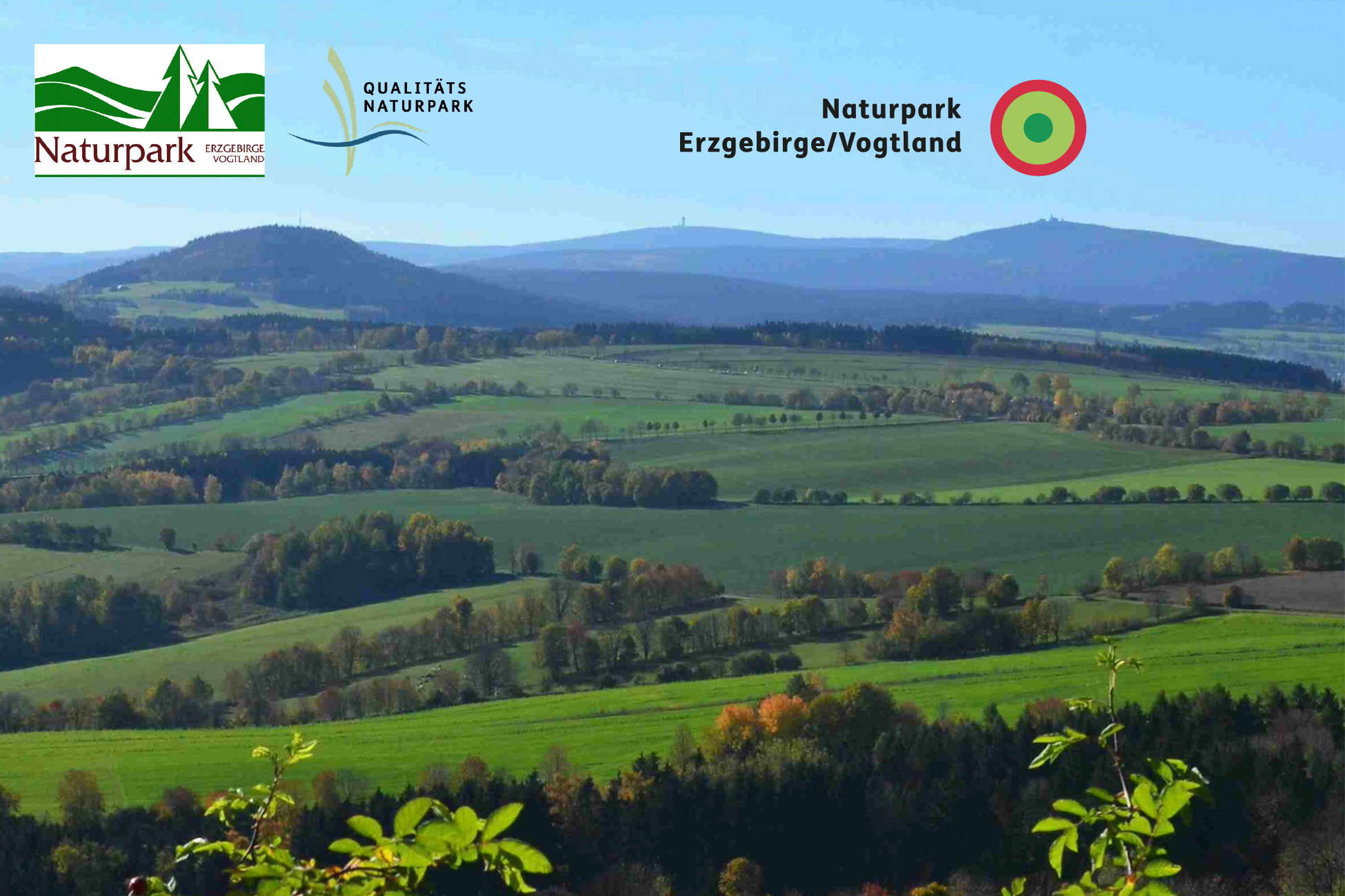 Sportpark Rabenberg EURORANDO 2026 Aussteller: Naturpark Erzgebirge/Vogtland Hügelige Landschaft im Naturpark Erzgebirge/Vogtland mit grünen Feldern und Bäumen.