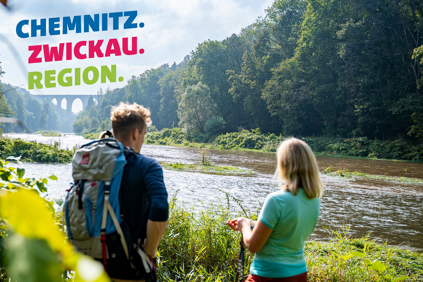 Sportpark Rabenberg EURORANDO 2026 Aussteller: Tourismusverband Chemnitz Zwickau Region e.V.; © Oliver Goehler Wanderer blicken auf Fluss und historische Steinbogenbrücke in der Region Chemnitz-Zwickau